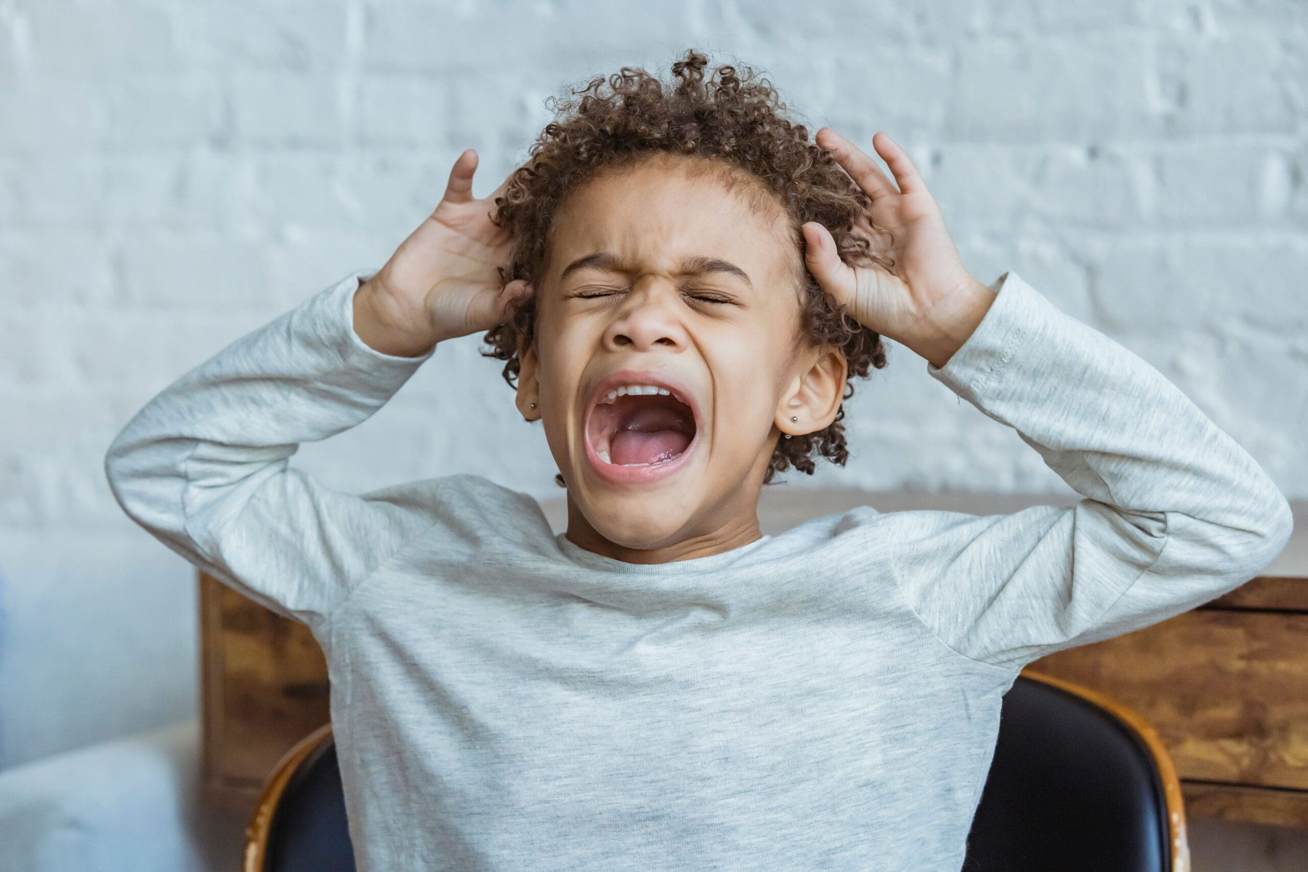 child screaming while holding his head feeling anxious